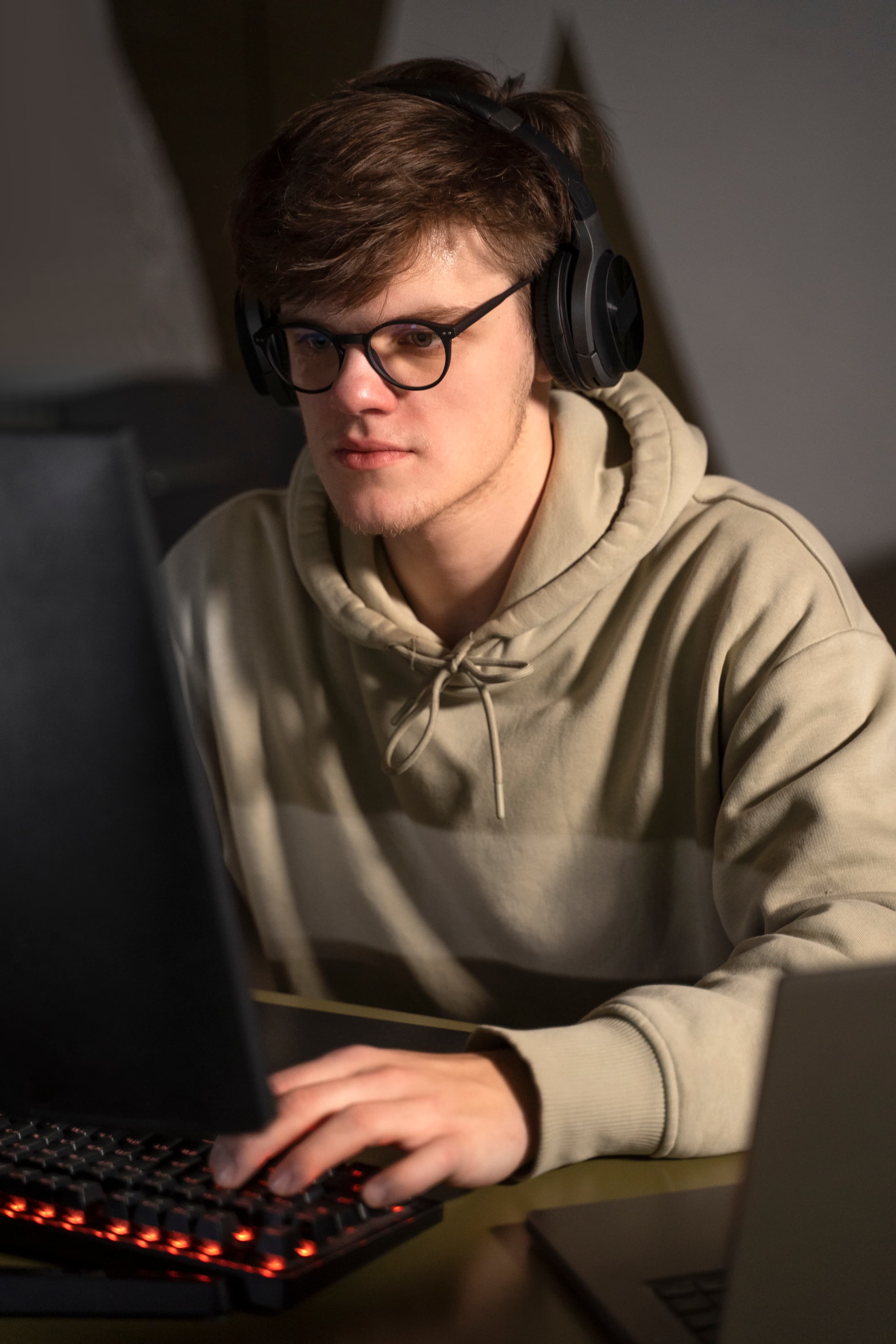 Chłopak w słuchawkach przy komputerze z podświetlaną klawiaturą, profil technik informatyk i programowanie.