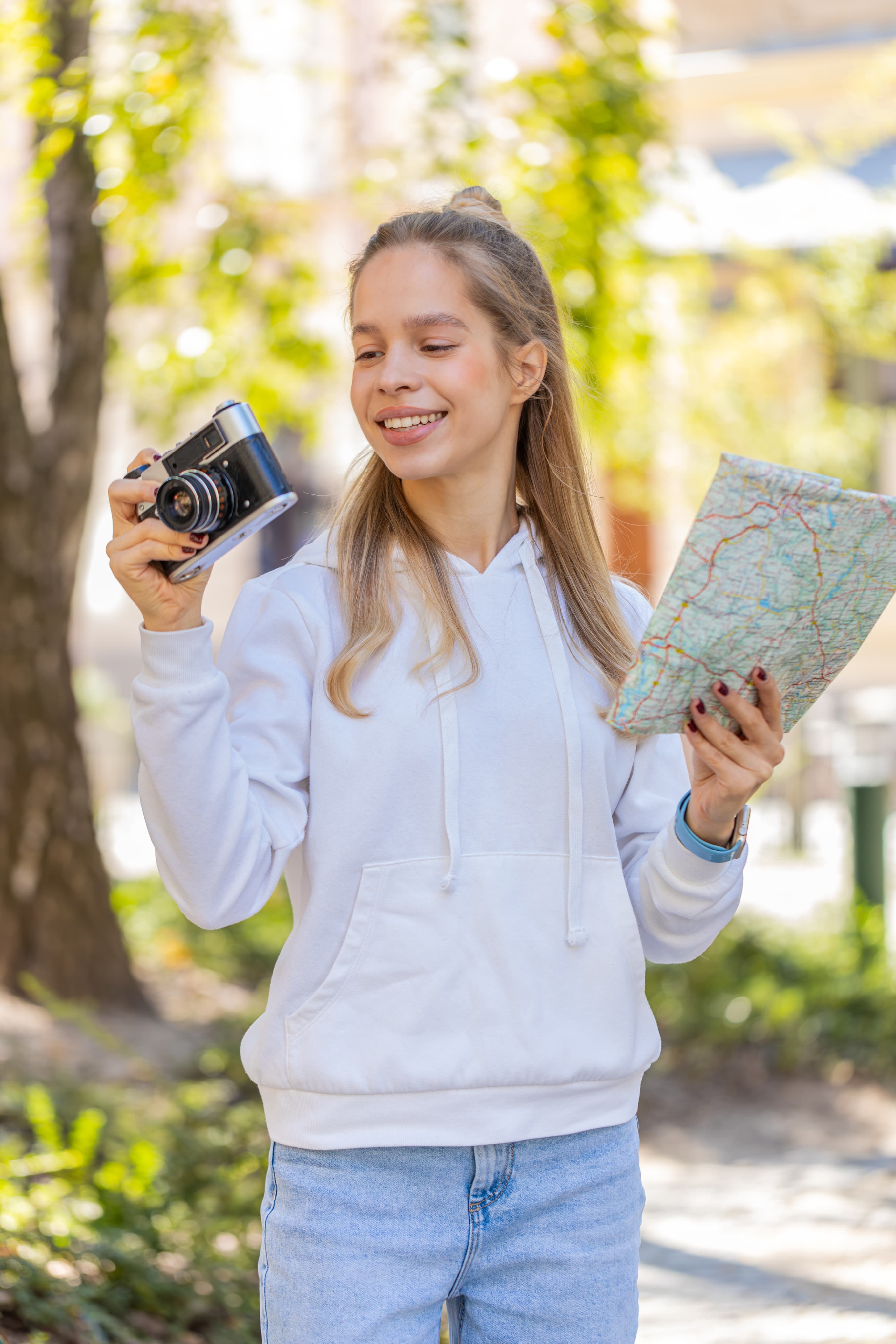 Dziewczynka z aparatem i papierową mapą w parku, profil matematyczno‑geograficzny z pasją do podróży i odkrywania świata.