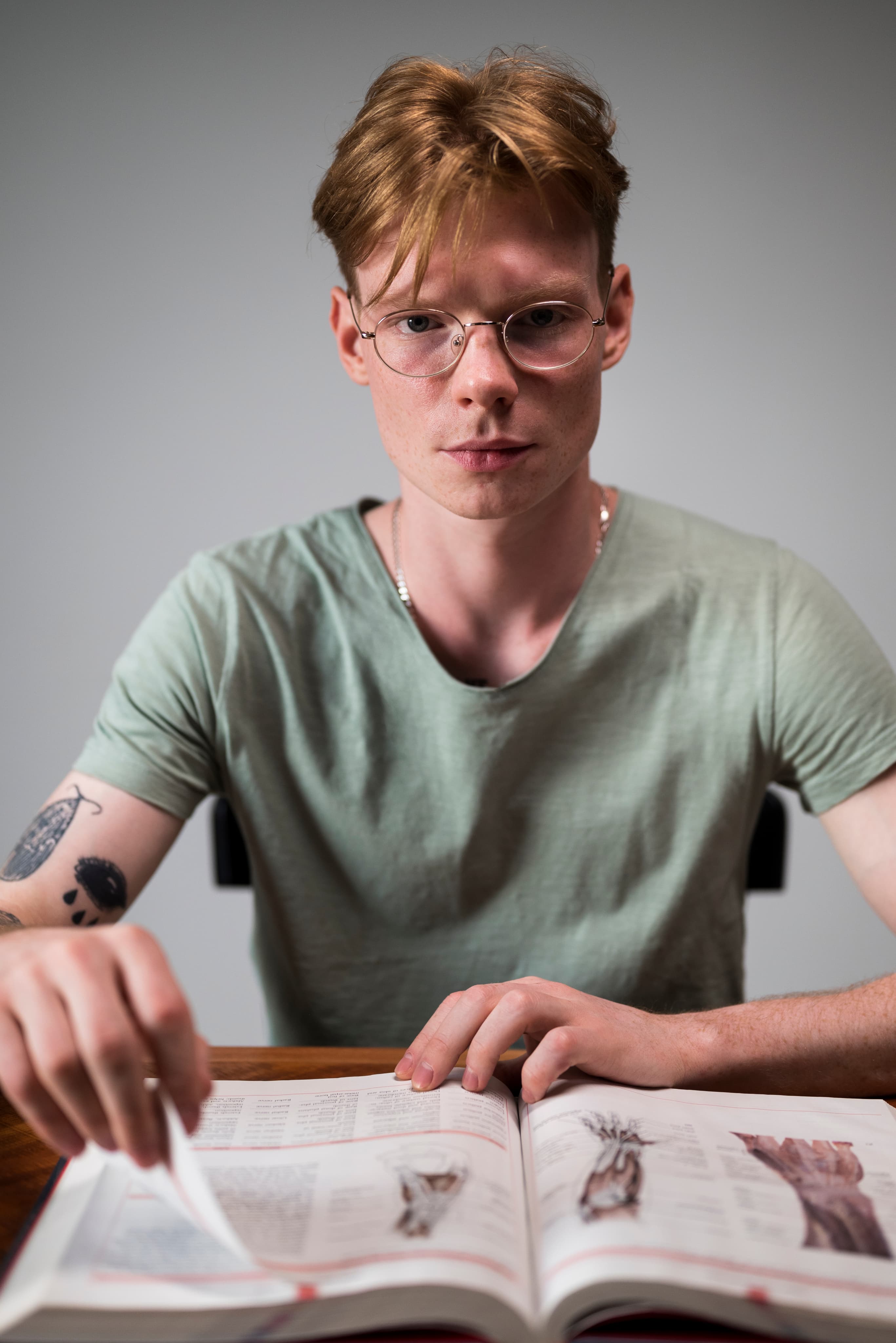 Nastolatek przeglądający grubą książkę historyczną przy biurku, profil humanistyczny z zamiłowaniem do historii.