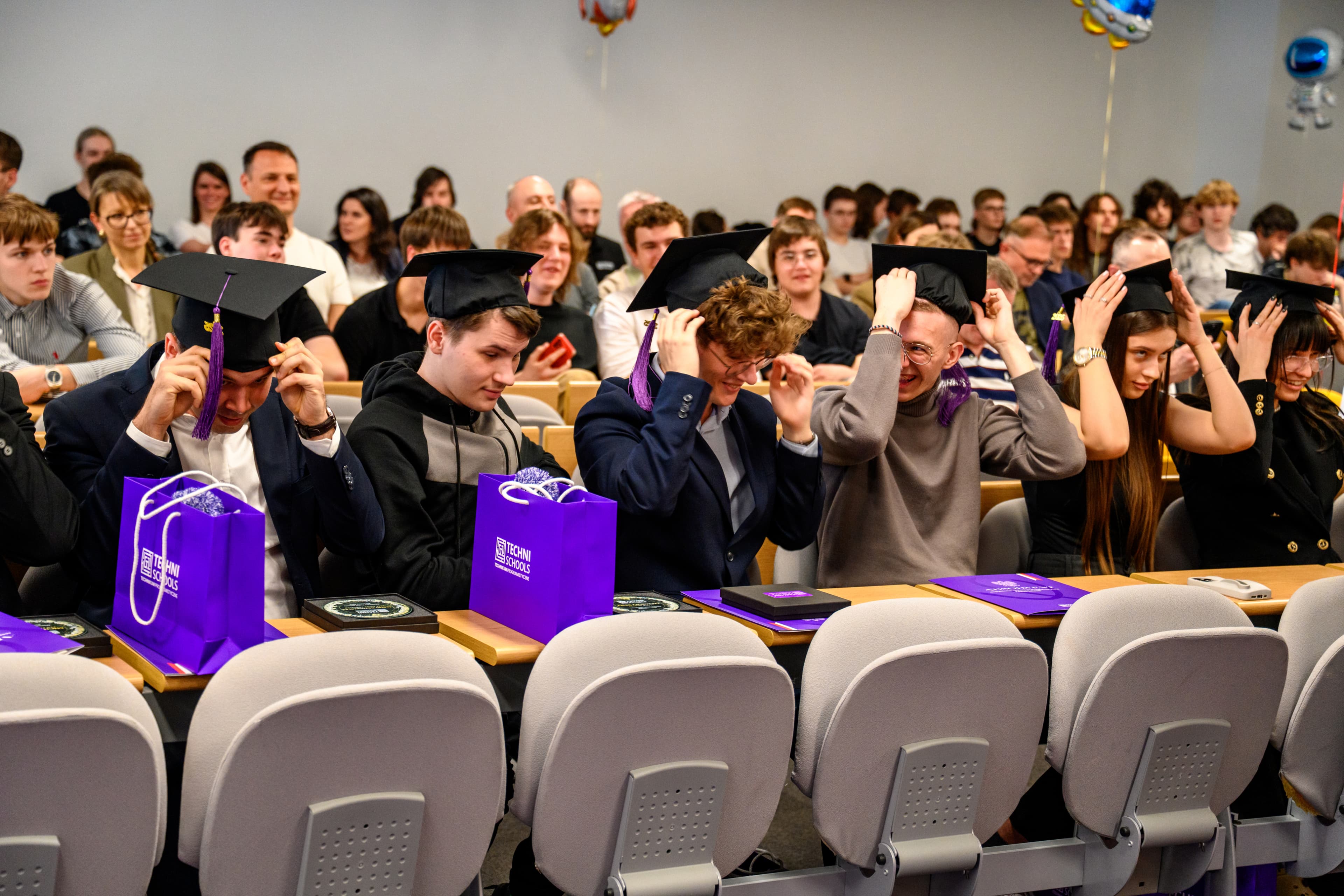 Absolwenci TechniSchools zakładają birety na uroczystości ukończenia szkoły